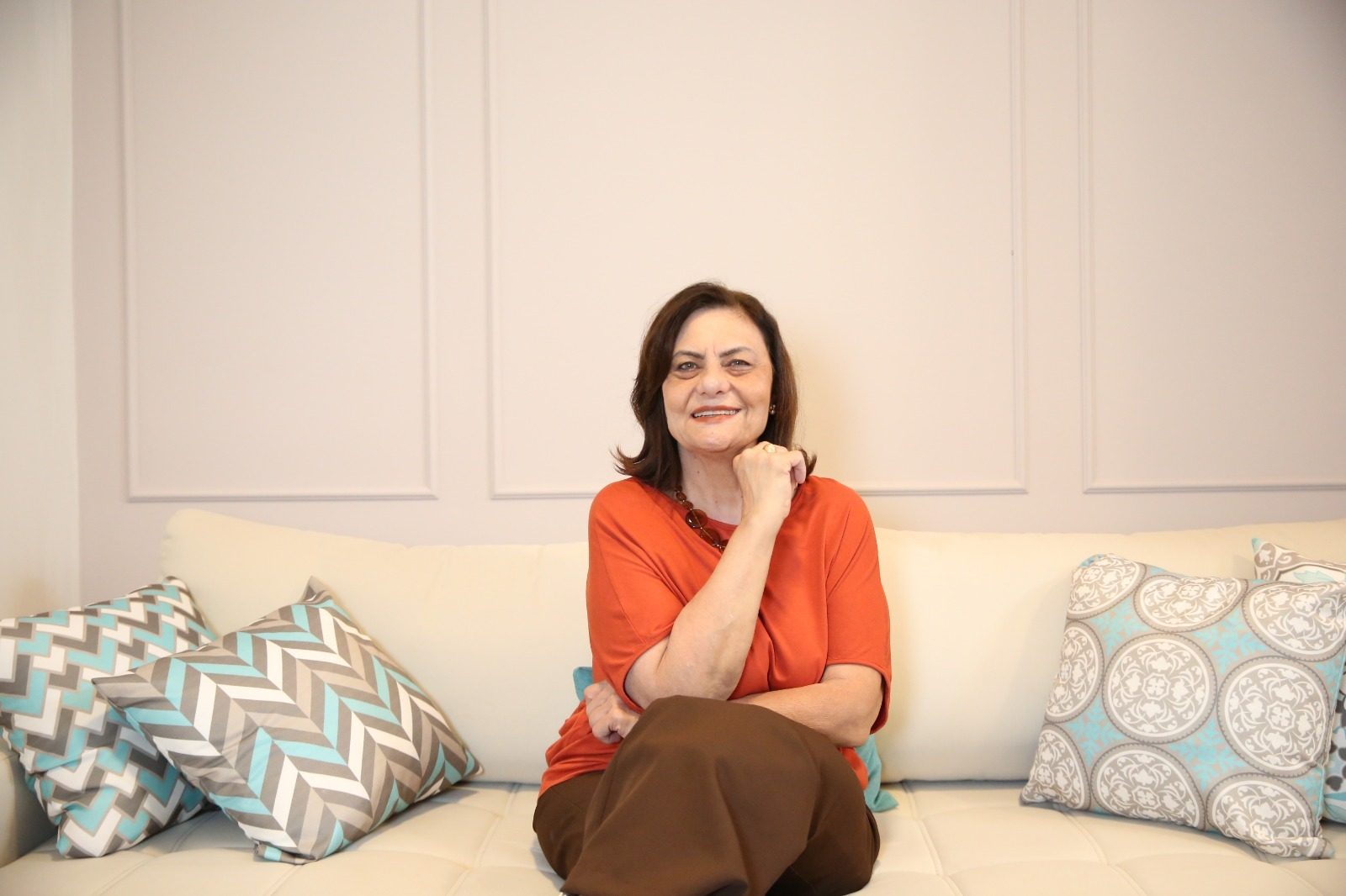 Cristiane Ribeiro sorrindo, sentada no sofá do consultório